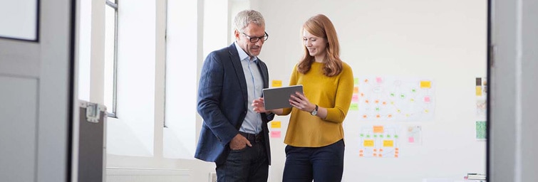 A businesswoman showing a businessman an image on a tablet