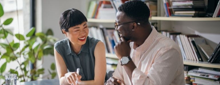 A businesswoman and businessman sitting in an office smiling