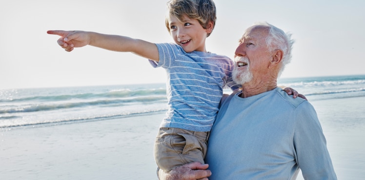 A grandfather holding his grandson on the beach