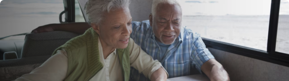 A retired man and woman in a van looking over a map